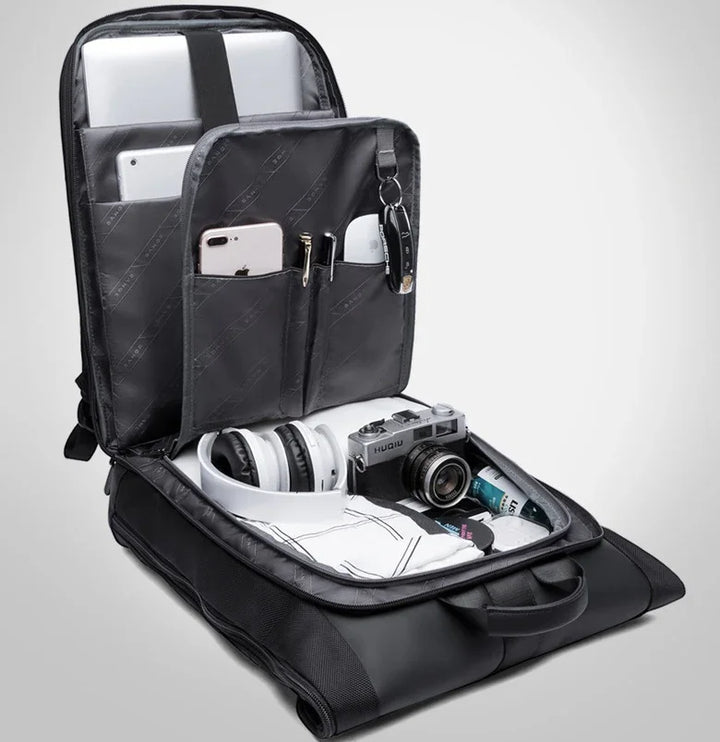 Open black tech backpack with organized compartments holding laptop, tablet, smartphone, camera, headphones, and accessories