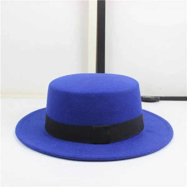 Blue wide-brim wool hat with black ribbon band on white surface and white background