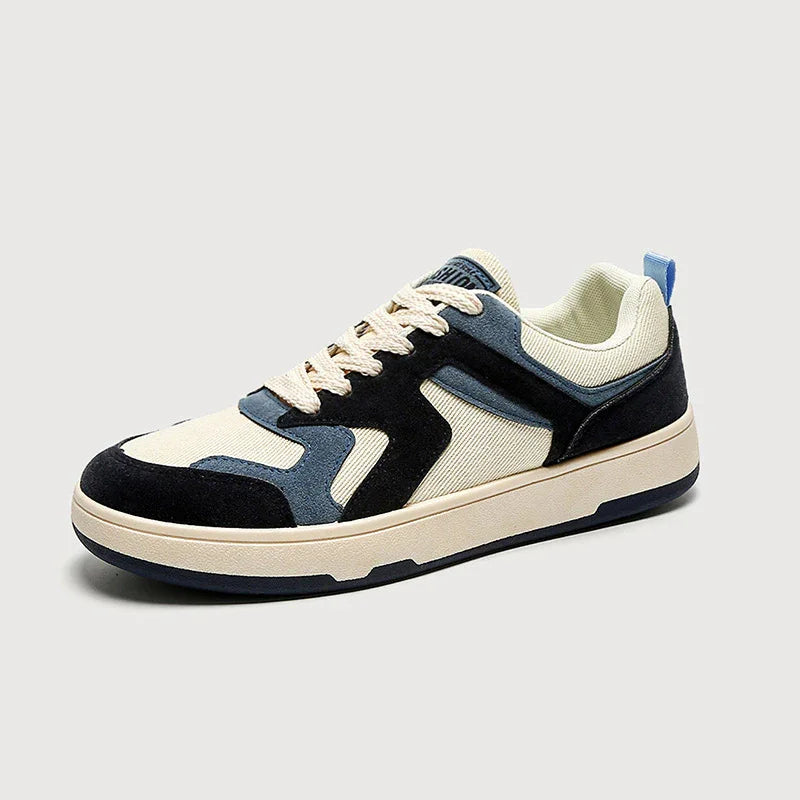 Casual sneaker shoe with cream canvas, black and blue suede accents, and beige sole on light gray background