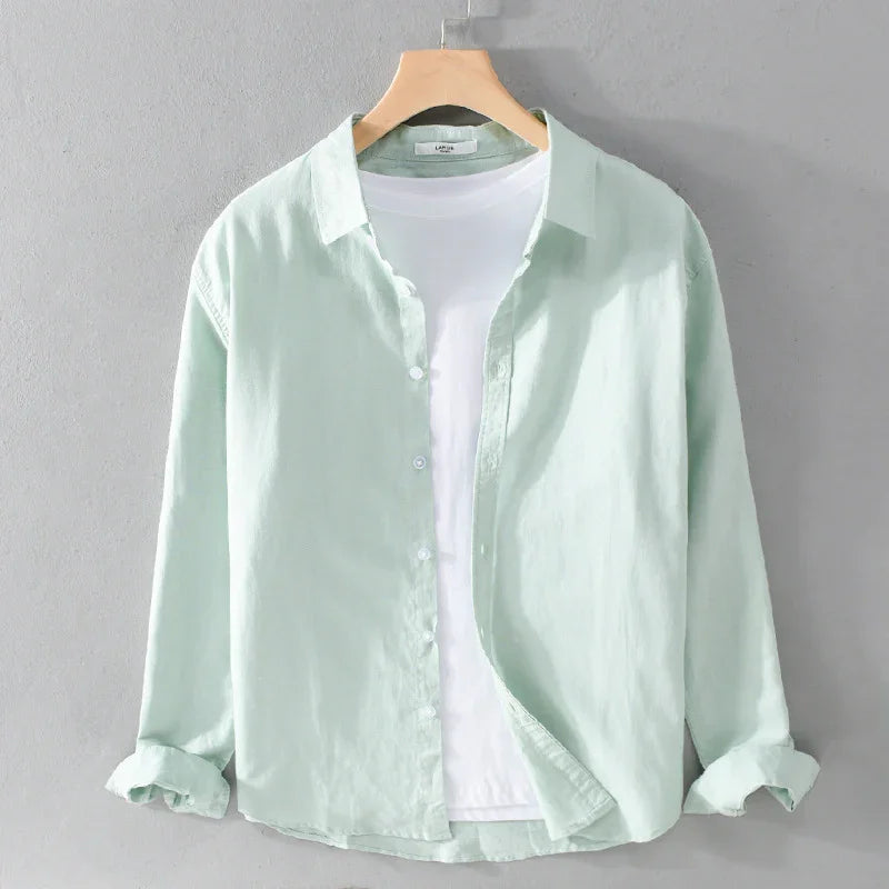 Light green linen shirt layered over white T-shirt on wooden hanger against gray wall