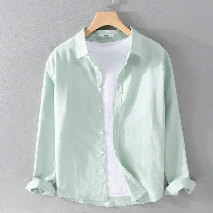 Light green linen shirt layered over white T-shirt on wooden hanger against gray wall