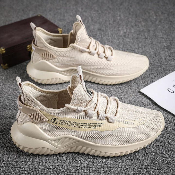 Beige lightweight knit sneakers with wavy soles and text detail, displayed on grey carpet