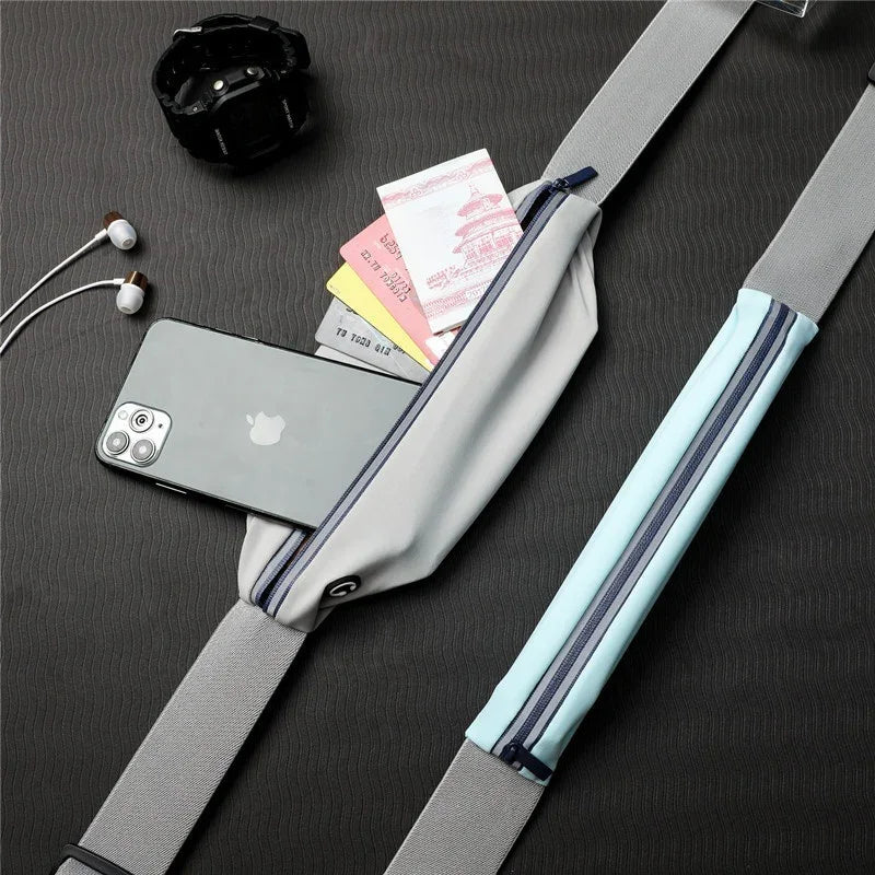 Gray crossbody travel sling bag with phone, cash, cards shown, beside watch and earphones