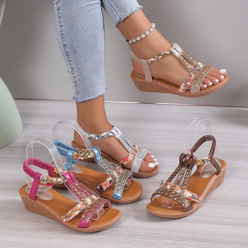 Women's wedge sandals in gold, silver, blue, pink, and brown with floral straps on wooden floor