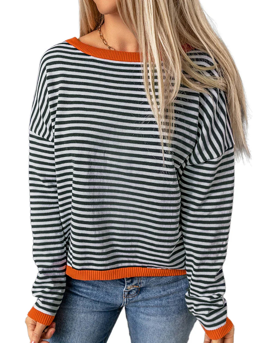 Woman wearing black and white striped long-sleeve sweater with orange trim and blue jeans
