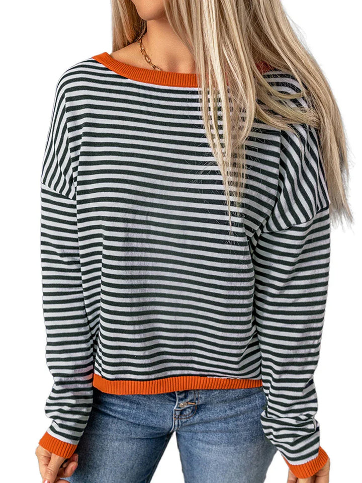 Woman wearing black and white striped long-sleeve sweater with orange trim and blue jeans