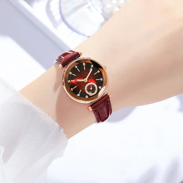 Elegant wristwatch with a round rose gold case, dark red sunburst dial, and maroon leather strap