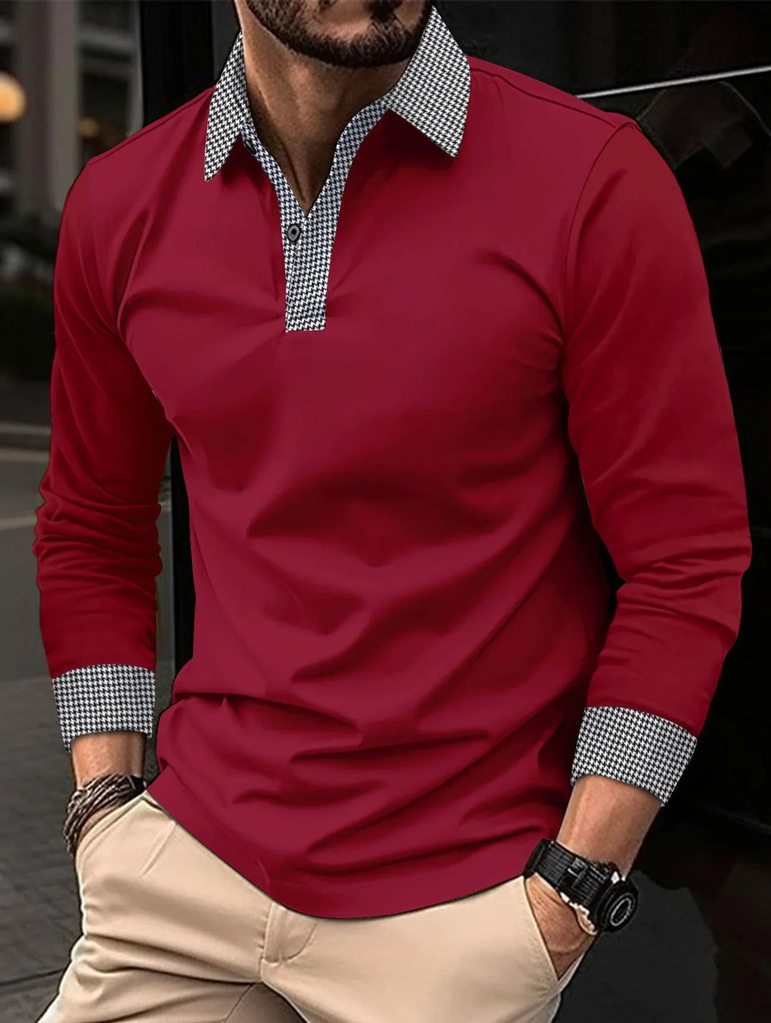 Man wearing a red long-sleeve polo shirt with black and white houndstooth collar and cuff details, paired with beige pants