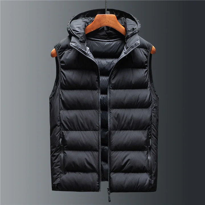 Black puffer vest with hood and front zipper on wooden hanger against gray background