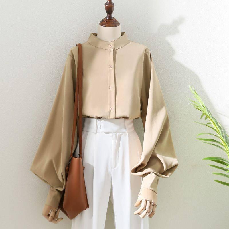 Beige button-up blouse with puff sleeves paired with high-waisted white pants and brown leather shoulder bag