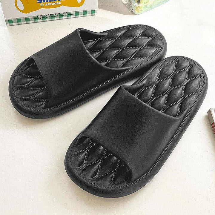 Pair of black quilted leather open-toe slide sandals on white surface