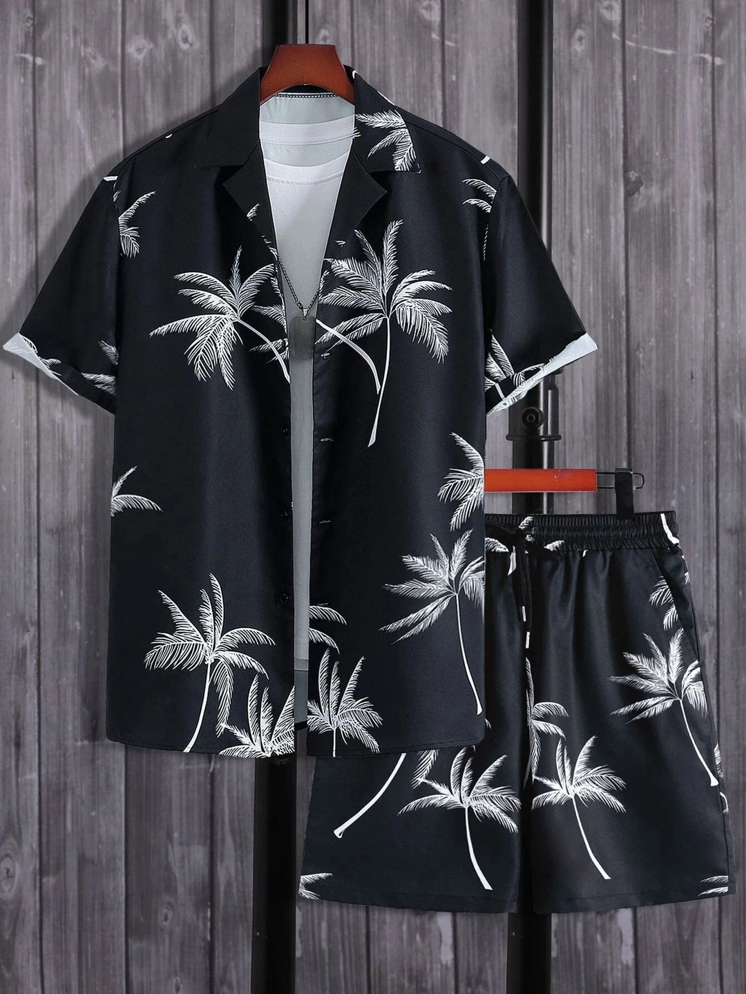 Black tropical palm tree print short sleeve shirt and matching shorts set on wooden background