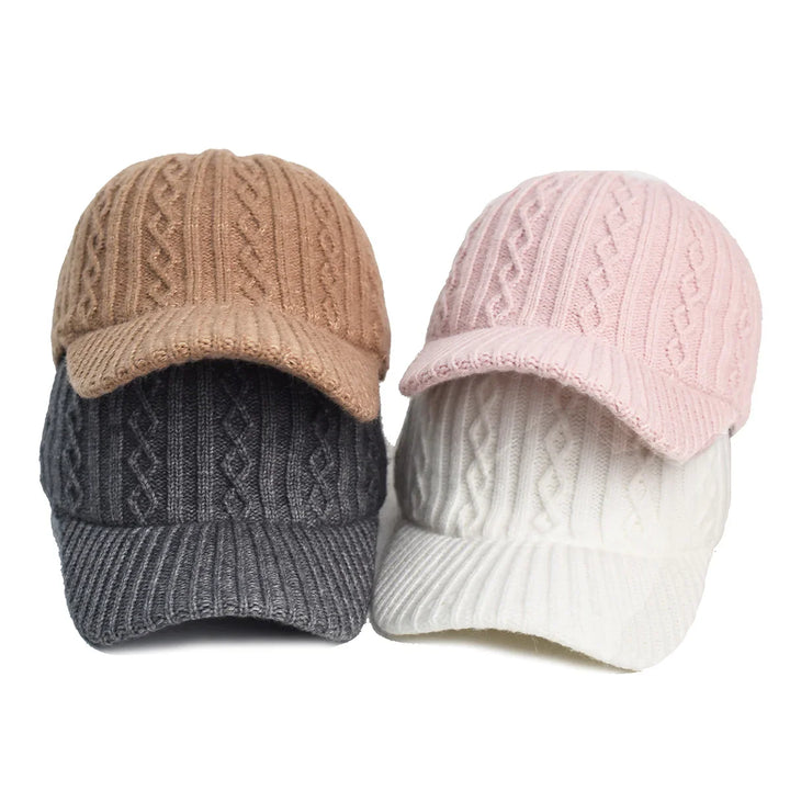 Four knitted cable pattern baseball caps in camel, pink, dark gray, and white colors on white background