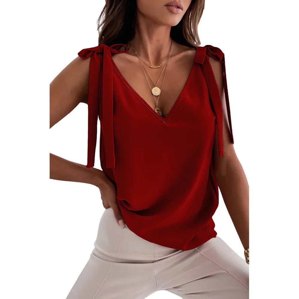 Woman wearing red sleeveless V-neck top with shoulder ties and beige pants