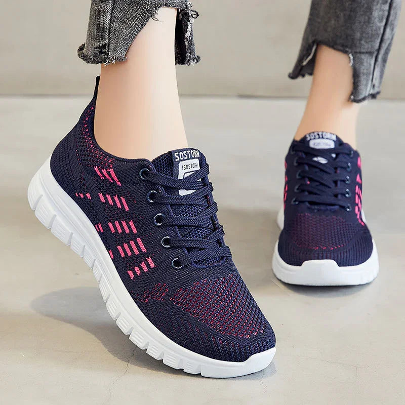 Navy blue and pink breathable knit sneakers with white soles worn with cropped gray jeans