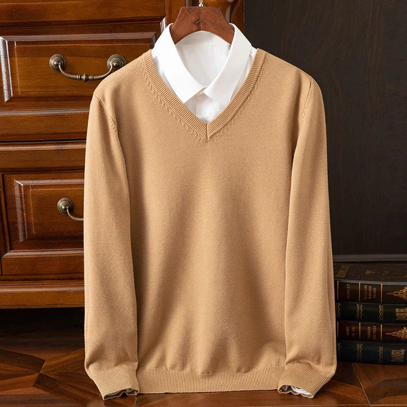 Beige V-neck sweater layered over a white dress shirt on wooden hanger with vintage furniture background