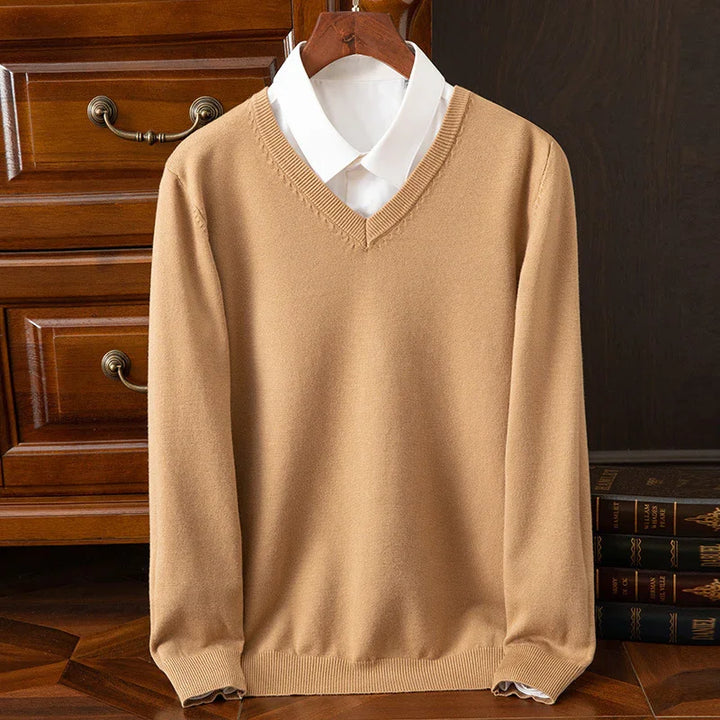 Beige V-neck sweater layered over a white dress shirt on wooden hanger with vintage furniture background