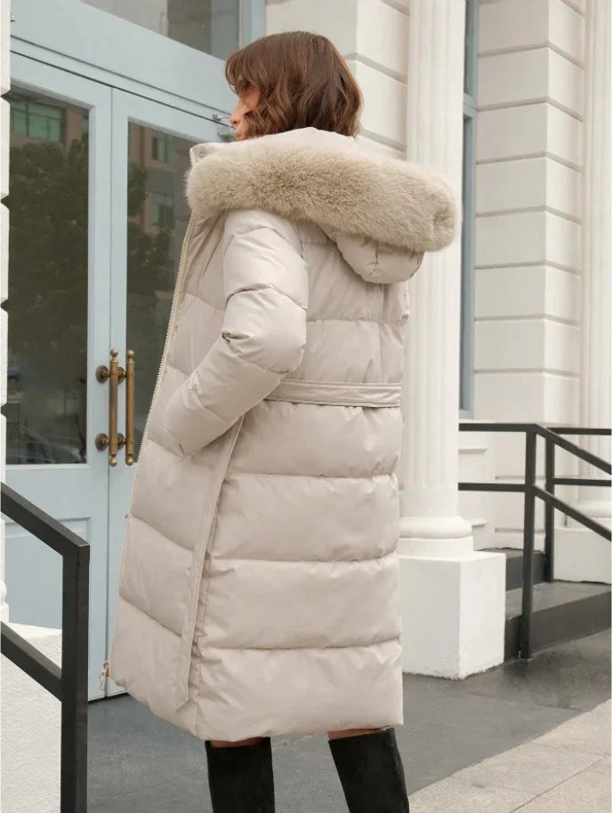 Woman wearing beige puffer coat with fur hood outdoors near building entrance