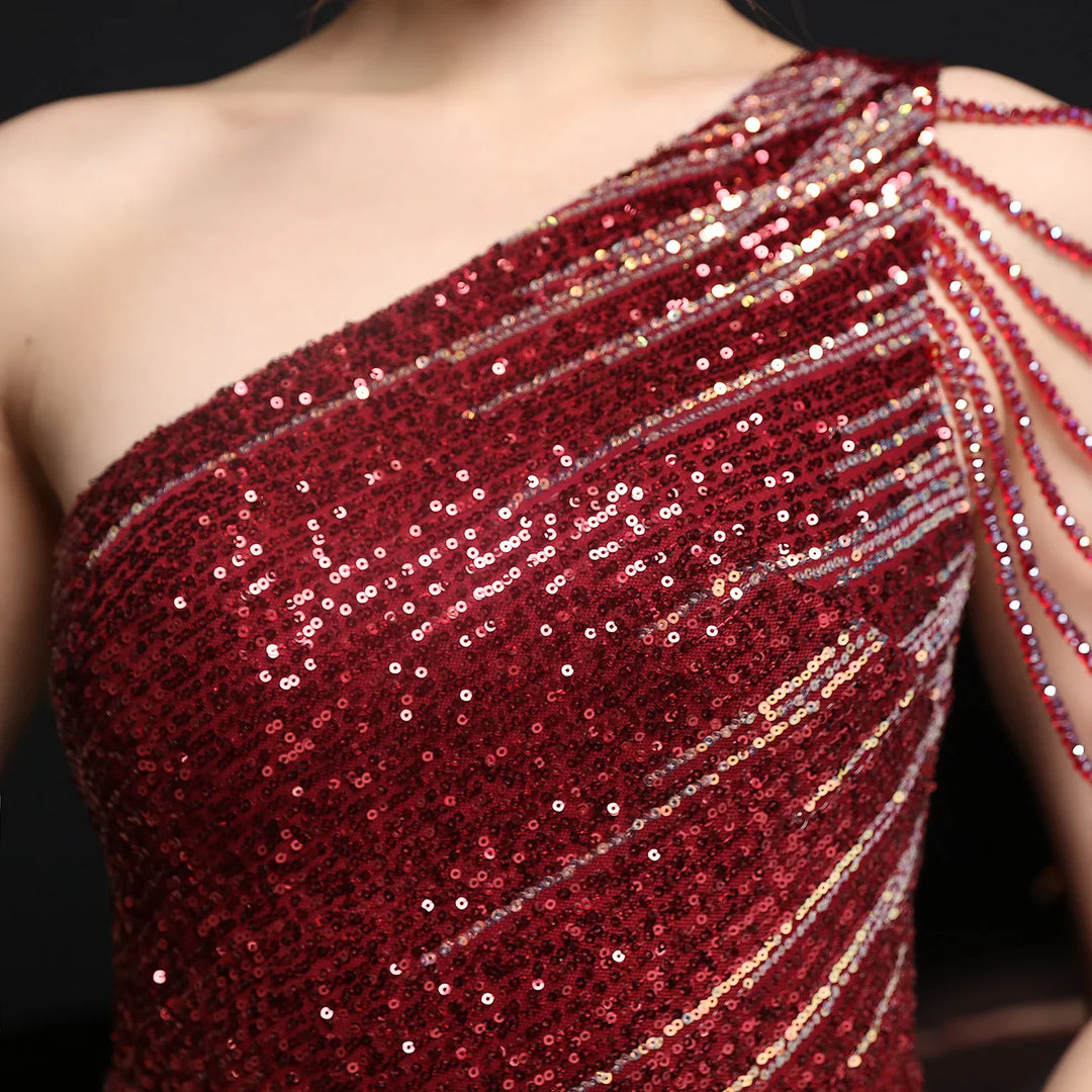 Close-up of a woman wearing a red sequined one-shoulder dress with decorative fringe