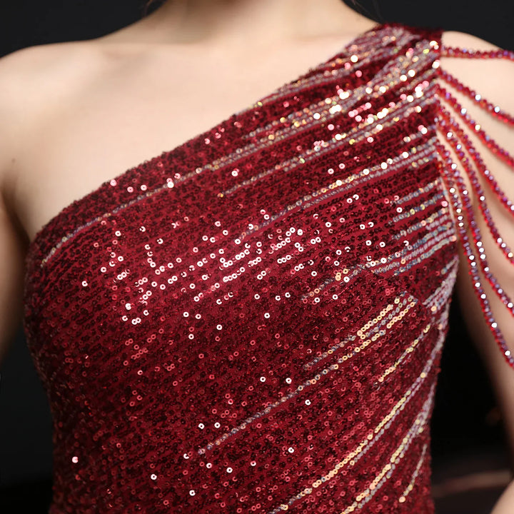 Close-up of a woman wearing a red sequined one-shoulder dress with decorative fringe
