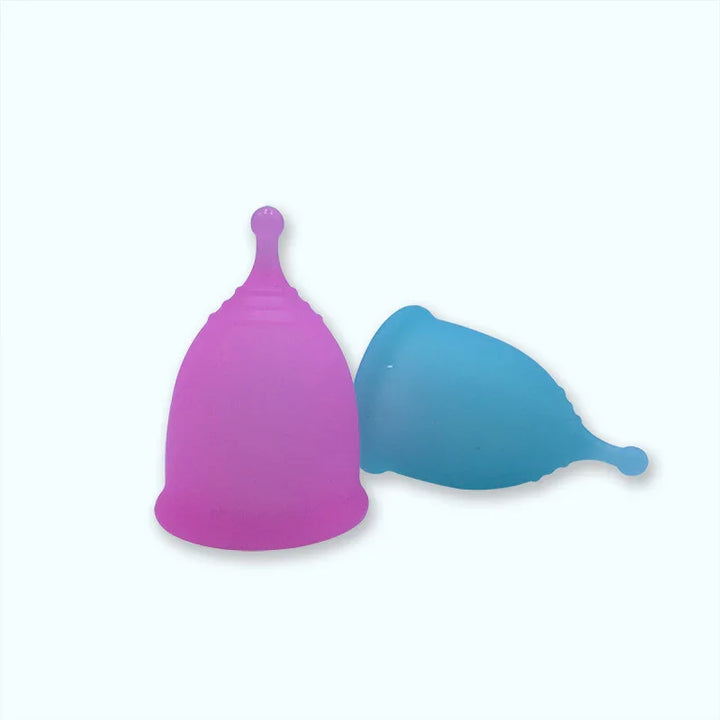 Two menstrual cups, one purple standing upright and one blue lying down, on a white background
