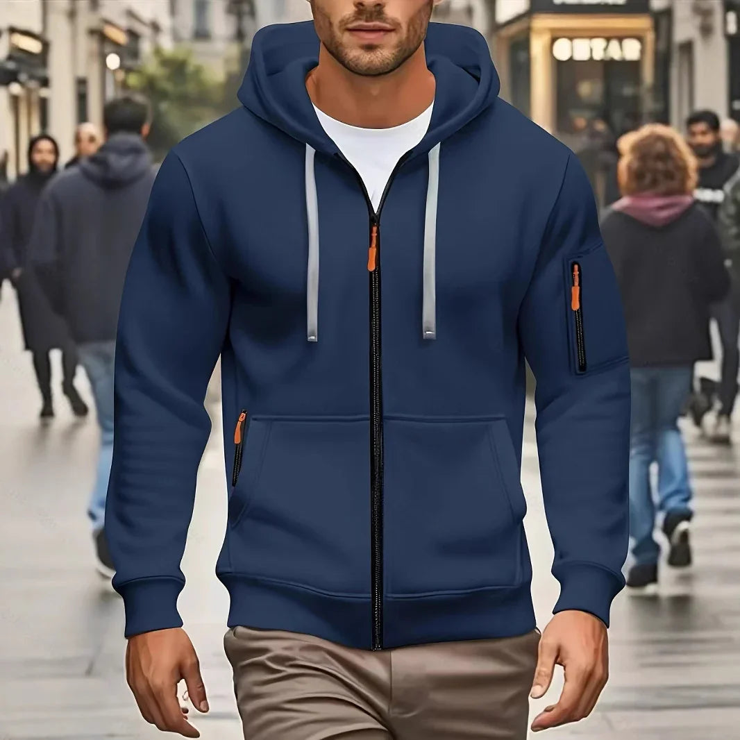 Man wearing navy blue zip-up hoodie with front and sleeve pockets walking on city street