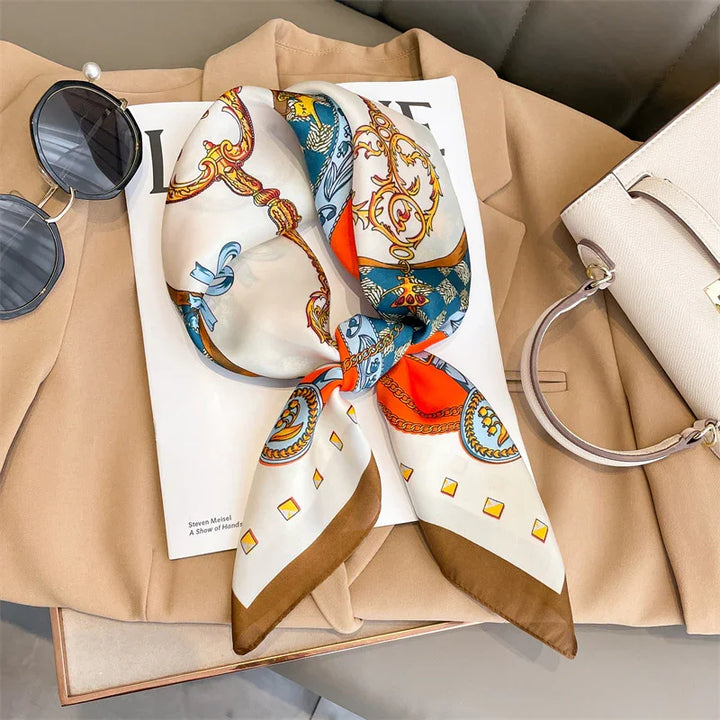 Colorful patterned silk scarf on a fashion magazine, beige coat, sunglasses, and white handbag
