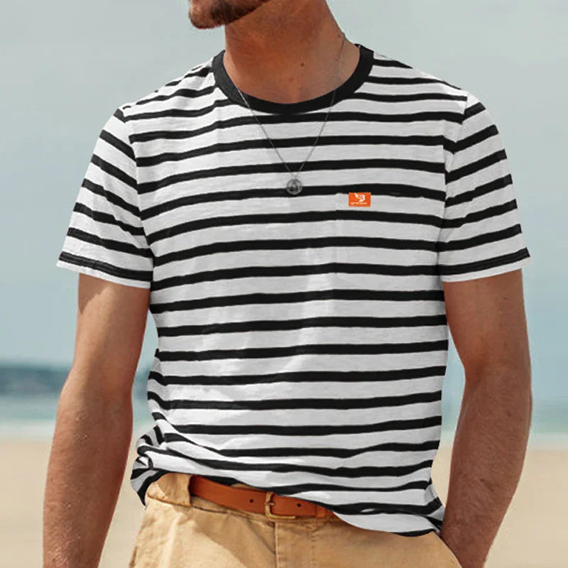 Man wearing a black and white striped T-shirt with a small orange logo on chest at the beach