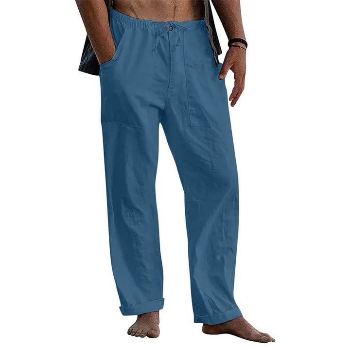 Man wearing casual loose blue cotton pants with elastic waist and pockets, barefoot