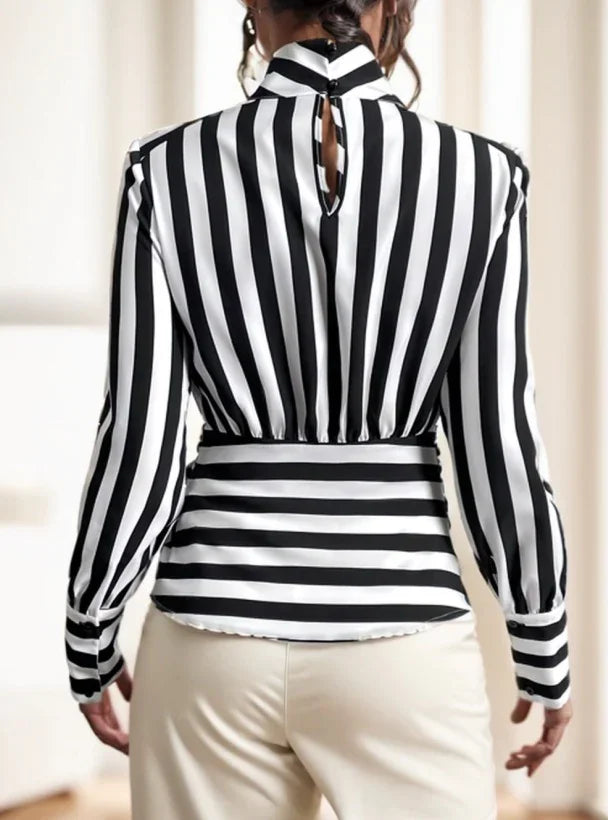 Back view of woman wearing black and white vertical striped blouse with high neck and keyhole detail