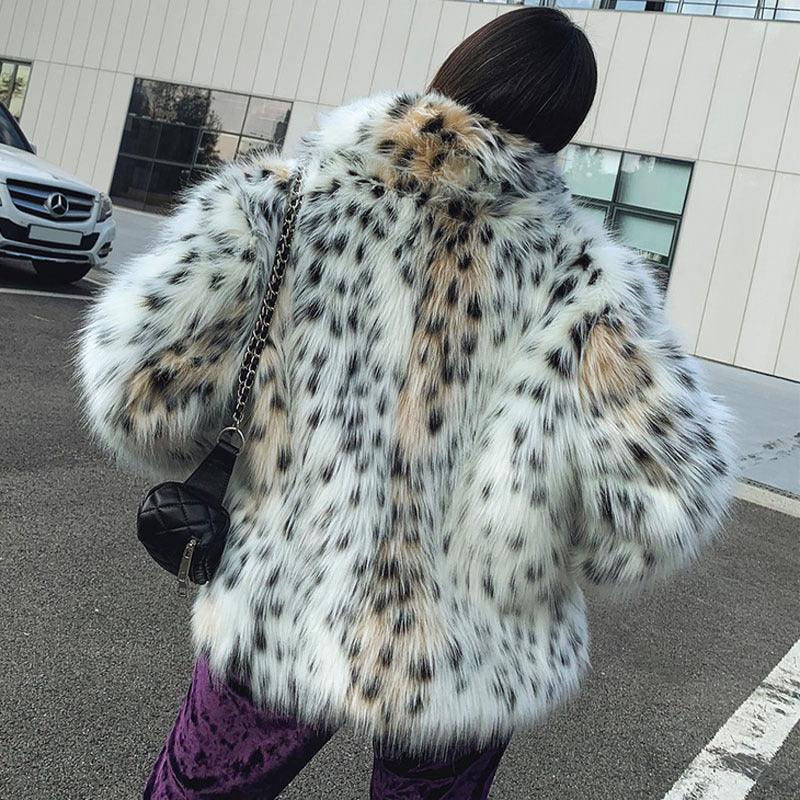 Person wearing white and black spotted faux fur coat with leopard print pattern, standing outdoors near a parked white Mercedes