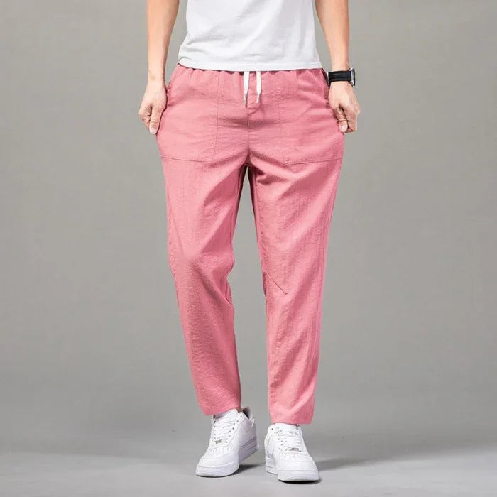Person wearing casual pink drawstring pants with front pockets and white sneakers on gray background