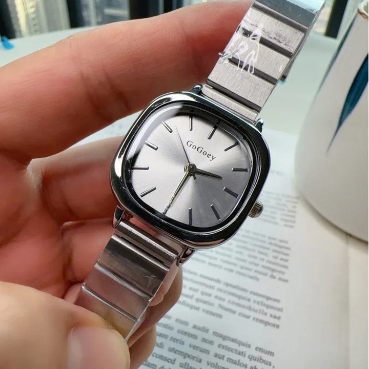 Close-up of a silver GoGoey wristwatch with a square face and stainless steel band held in hand