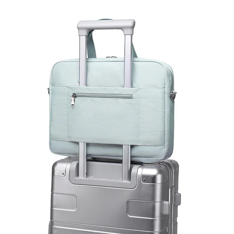 Light blue laptop bag attached to handle of silver hard-shell rolling suitcase