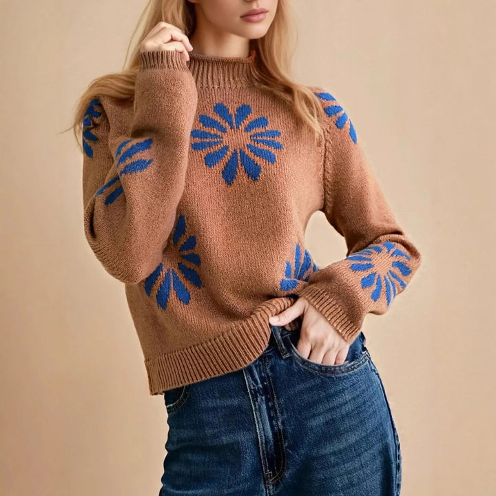 Woman wearing brown knit sweater with blue flower patterns paired with blue jeans