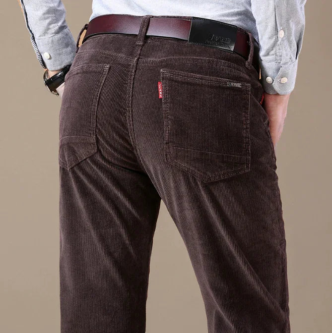 Back view of man wearing dark brown corduroy pants with brown leather belt and light blue shirt