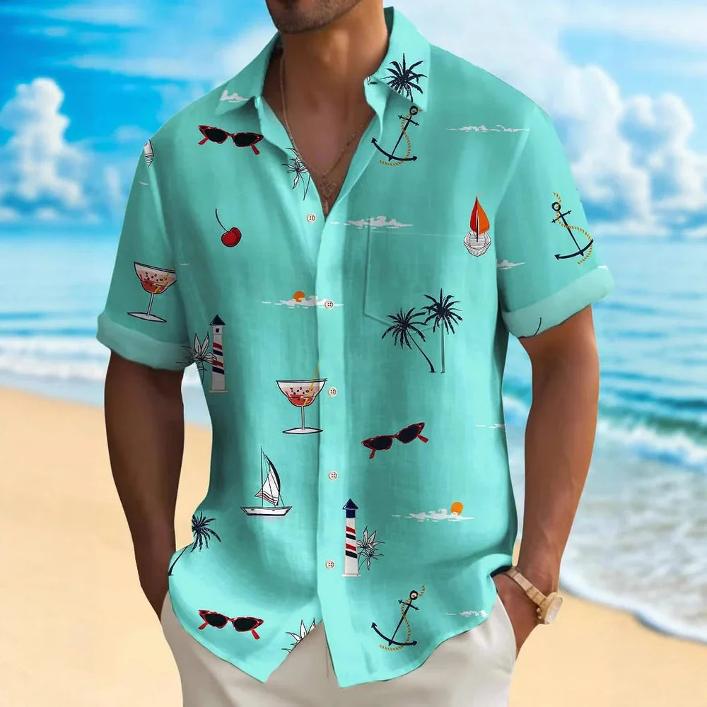 Man wearing turquoise tropical print short-sleeve shirt with anchors, palm trees, sunglasses at beach