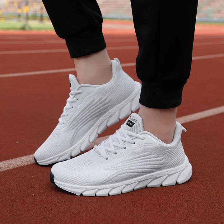 Person wearing white lightweight sports running shoes on red track surface