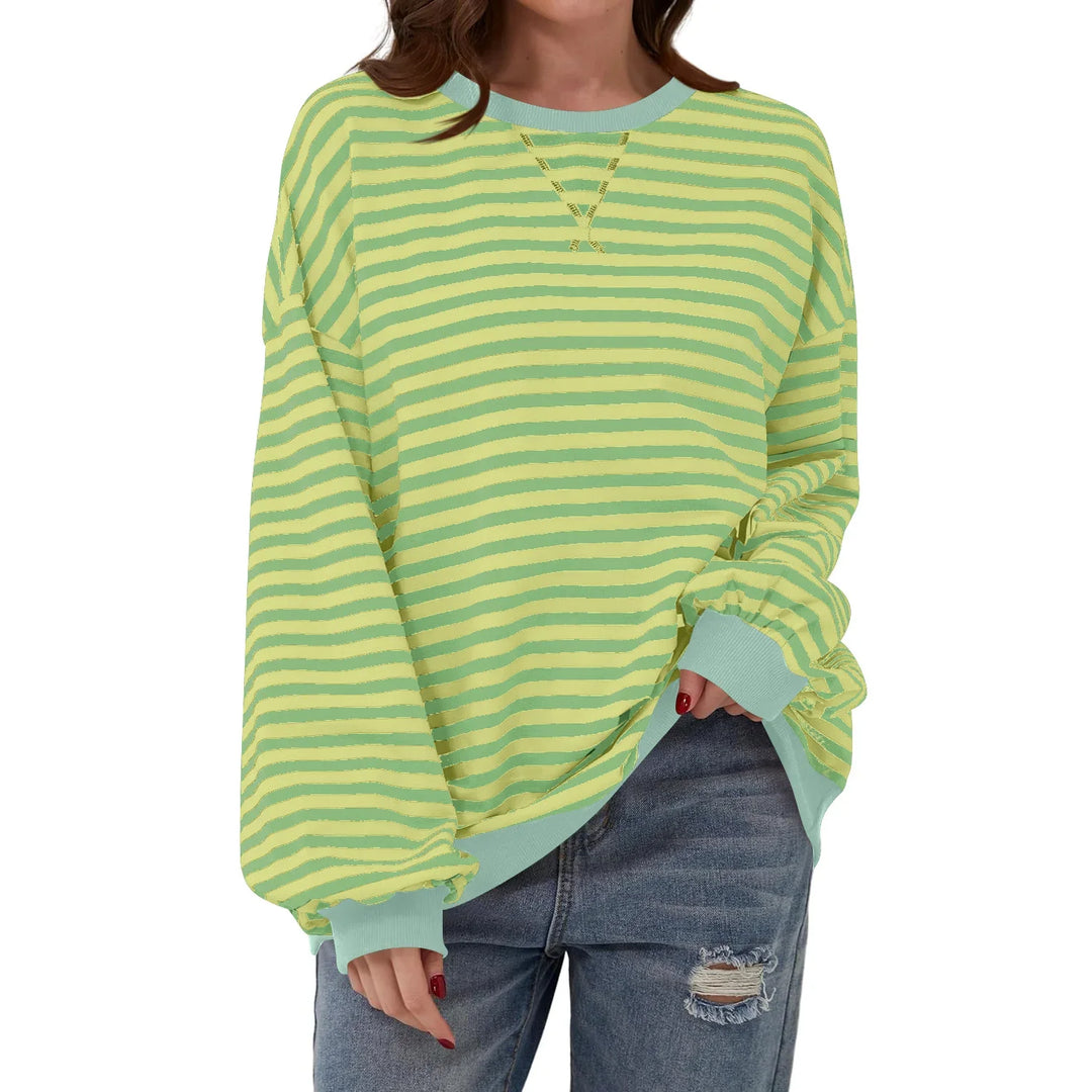 Woman wearing oversized yellow and green striped sweatshirt with light blue cuffs and ripped jeans
