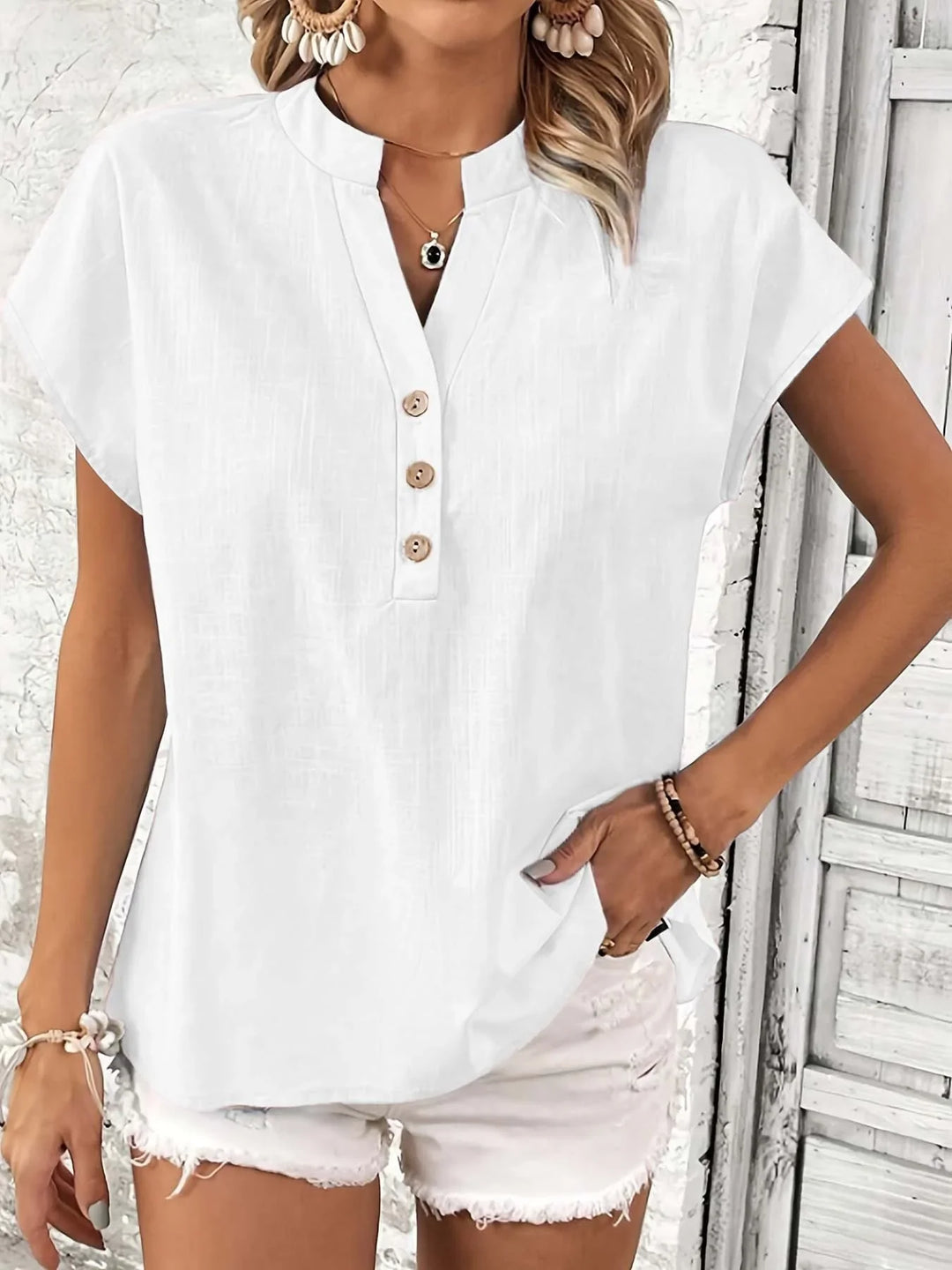 Woman wearing casual white short sleeve blouse with buttons and distressed white shorts