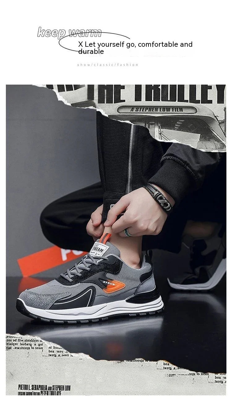 Person wearing gray and black sports sneakers with orange accents, black jogger pants, and bracelets