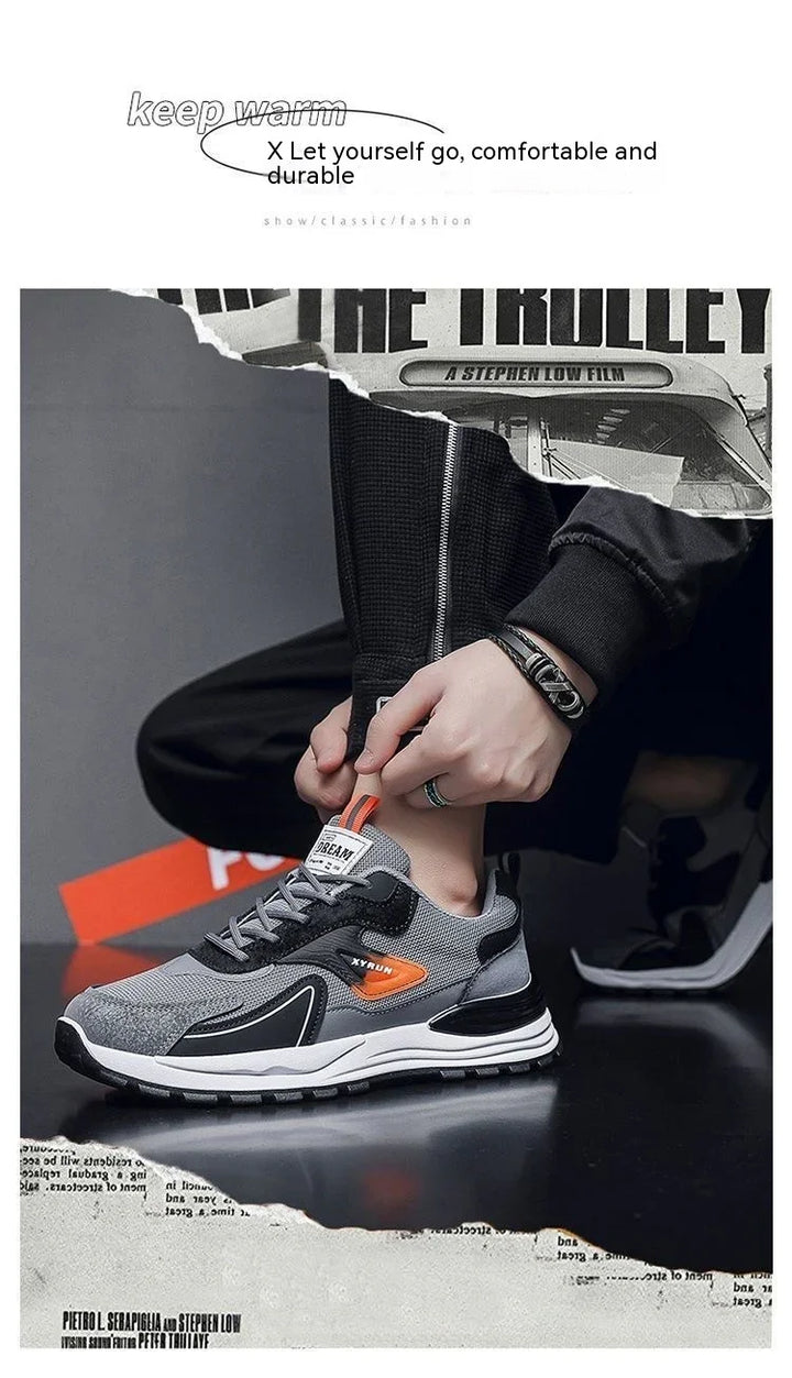 Person wearing gray and black sports sneakers with orange accents, black jogger pants, and bracelets