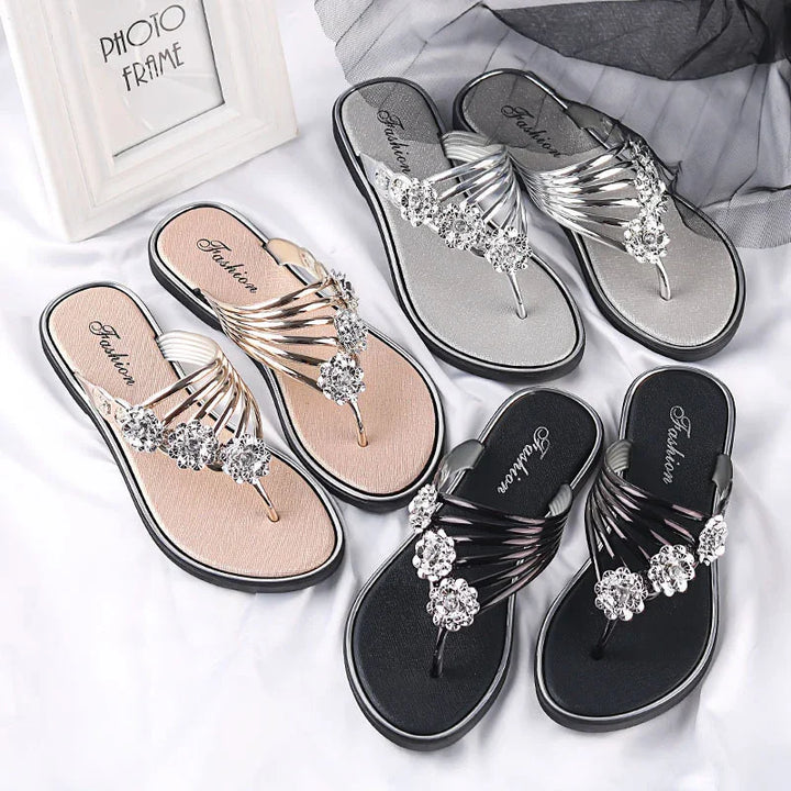 Three pairs of jeweled fashion thong sandals in beige, silver, and black on white background