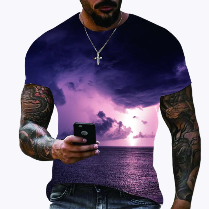 Man with tattooed arms wearing a t-shirt featuring a purple lightning storm over ocean at sunset