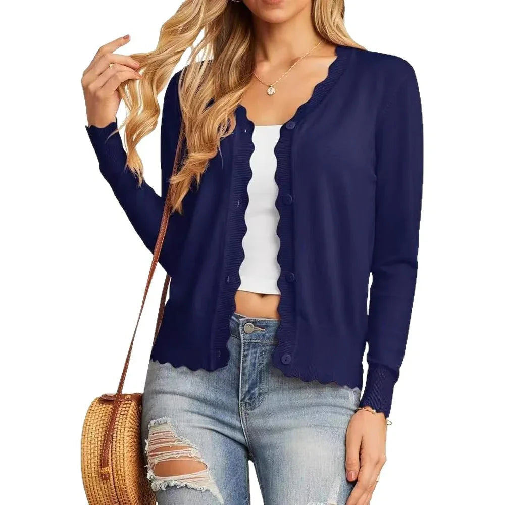woman wearing navy blue scalloped edge button-up cardigan with white crop top and ripped jeans
