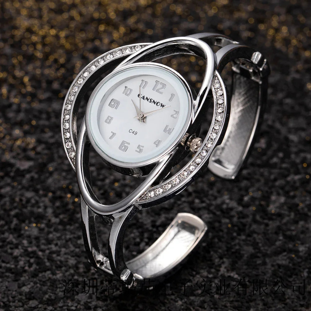 Silver women's wristwatch with white dial, crystals on bezel, and metal open bangle band