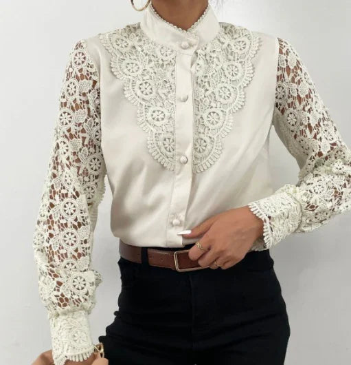 Woman wearing white lace blouse with floral embroidered sleeves and high collar, paired with black pants