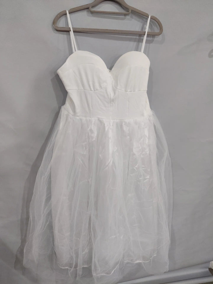 White sleeveless dress with fitted bodice and tulle skirt hanging on beige hanger