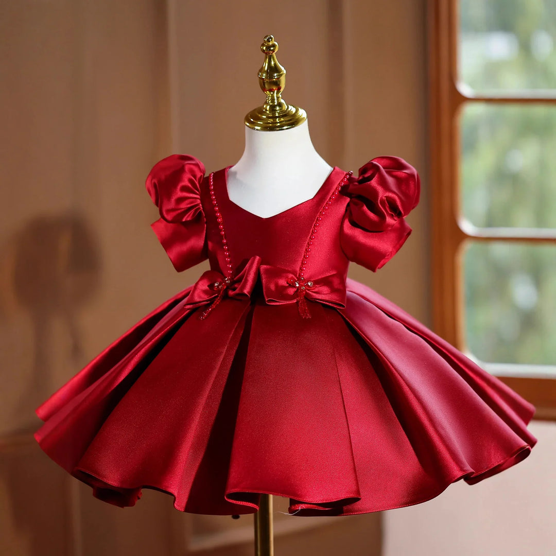 Elegant red satin baby dress with puff sleeves and bows displayed on mannequin