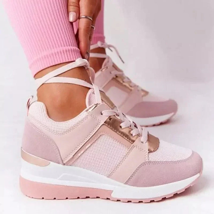 Stylish pink and white women’s wedge sneakers with mesh and suede details, worn with pink ribbed leggings
